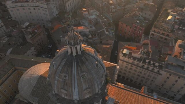 Aerial orbit Catholic Cathedral Cusp dome revealing Rome Skyline Roma Italy, Historic Cityscape of city center, Basilica di Sant'Andrea della Valle at sunset