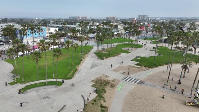 Overhead drone view of Marvin Braude Bike Trail in Venice Beach with beachfront properties, palm-lined paths, and ocean views beneath a cloudy sky.