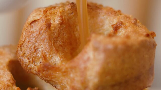 Close-up of Gravy Pouring into Yorkshire Pudding in Slow Motion with Classic Rustic Puffy Texture. Delicious British Roast Dinner Side Dish 4K.