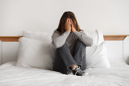 Sad young woman sitting in bedroom
