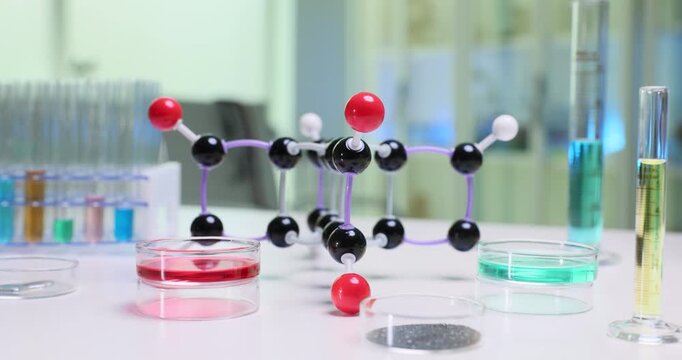 Complicated molecular structure model near color liquids and powder sample on desk. Essentials and equipment of modern chemical laboratory