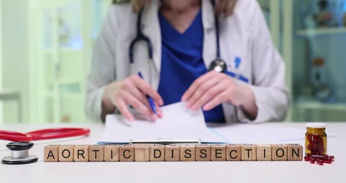 Text Aortic Dissection on wooden cubes near pills and stethoscope on table in clinic. Woman doctor checks patient records in medical office