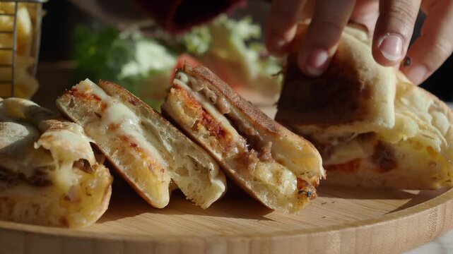 Close up video of hands picking up and showing delicious panini with cheese and tomato sauce.