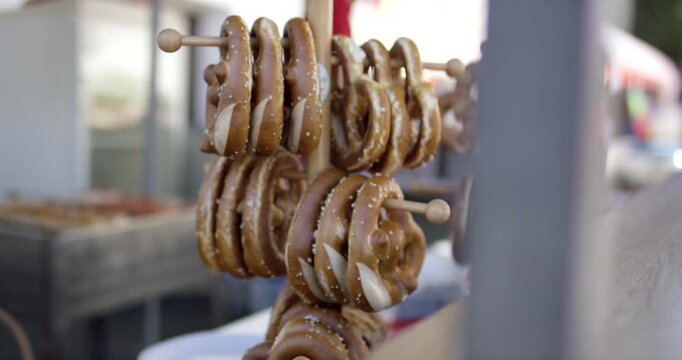 Close-up of fresh lye pretzels hanging on a traditional wooden display stand at an outdoor market stall