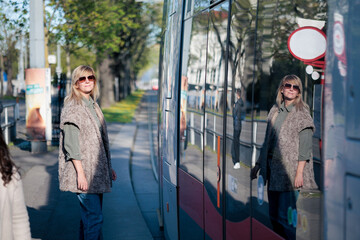 Obraz premium Woman waiting for tram at public transport stop