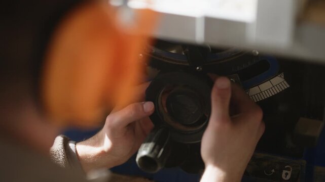 A close-up shot shows a person's hands meticulously adjusting the settings on a woodworking machine. The skilled individual carefully fine-tunes the saw for precise cuts in a workshop environment.
