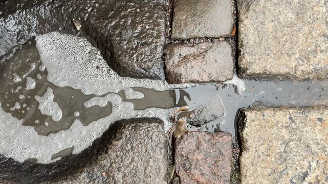 Water Flowing through Cobblestone Drainage Channel under Downspout in Helsinki