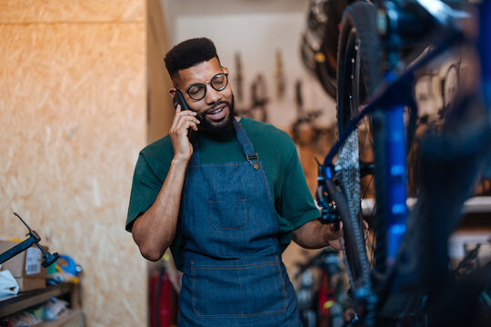 Bicycle mechanic talking on phone in repair shop