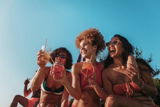 Diverse friends enjoying summer pool party with refreshing cocktails