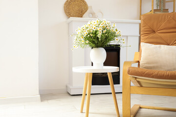 Obraz premium Vase with chamomiles on table in living room
