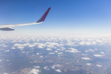 Obraz premium Aerial view from airplane window of wing over high altitude cloud cover.