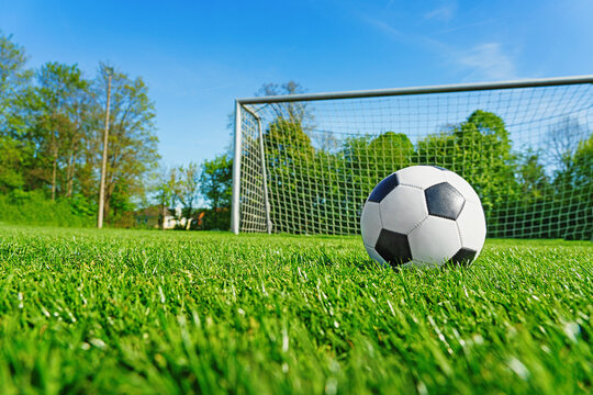 textured soccer game field with ball in front of the soccer goal. - center, midfield