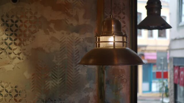 Warm industrial pendant light glows indoors reflecting on textured wall pattern.