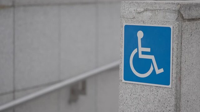 Wheelchair accessible sign on concrete wall by ramp entrance with cinematic slow movement.