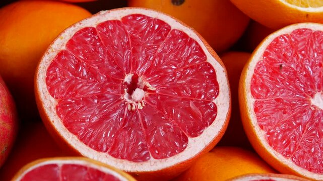 Fresh red grapefruit halves on display with orange fruits close up shot in natural light.
