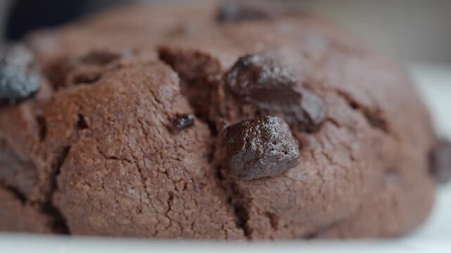 Macro footage of a large delicious chocolate chip cookie with rich texture.