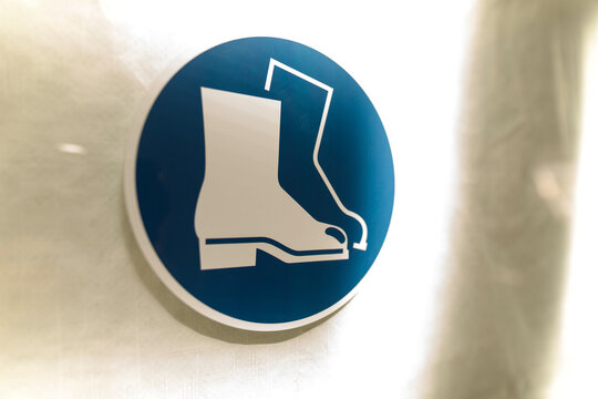 Safety boots sign on a white wall. Symbol of footwear protection. Signage indicating mand