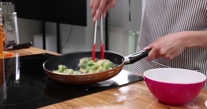 Person cooks broccoli in pan pouring egg mixture from bowl. Cook mixes vegetables setting omelet base while monitoring heat on surface time-lapse