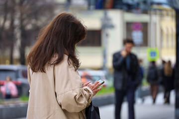 Fototapeta premium Woman using smartphone on spring city street