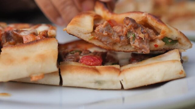 Traditional turkish pide with meat and peppers served on white plate at local restaurant.