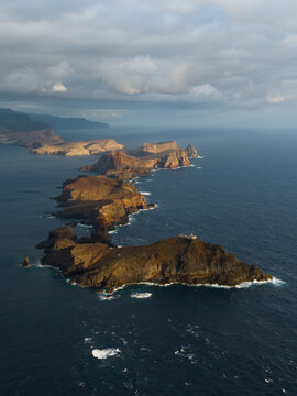 Aerial view of the rugged cliffs and volcanic rock formations of Ponta de Sao Lourenco stretching into the Atlantic Ocean under a cloudy sky in Canical, Madeira, Portugal.