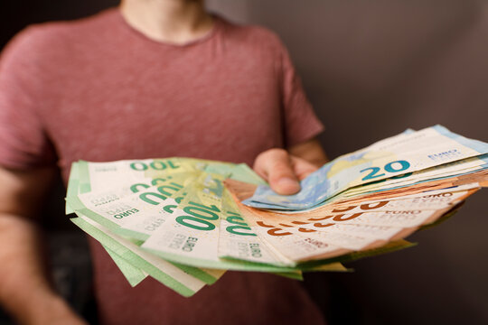 Close-up of person's hand holding euro banknotes, symbolizing wealth, finance, and financ
