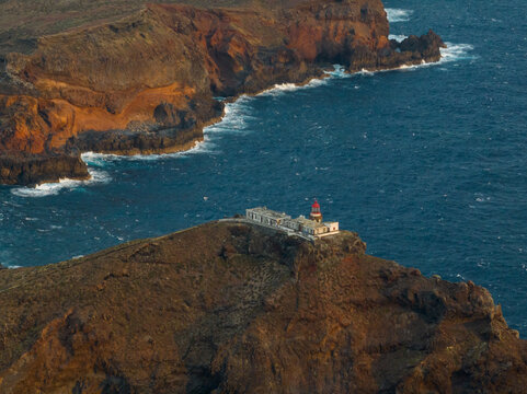 Aerial view of Ponta de Sao Lourenco lighthouse on a rocky cliff overlooking the Atlantic Ocean with crashing waves in Canical, Madeira, Portugal.