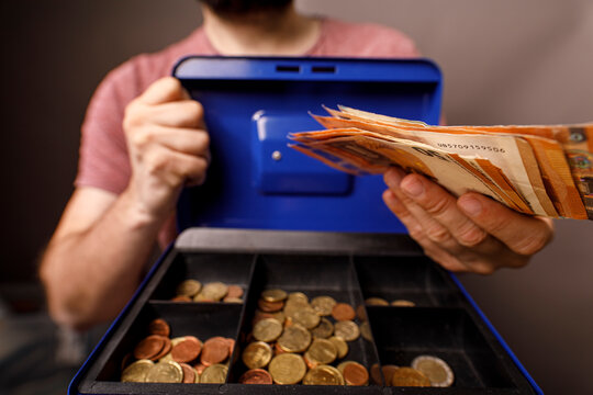 Close up of person counting money from a cash box, concept of finance, savings, and wealt