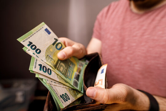 Close up of a man's hands with a wallet full of euro banknotes. Concept of finance, wealt