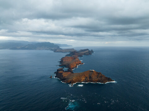 Aerial view of the rugged volcanic cliffs of Ponta de Sao Lourenco stretching into the Atlantic Ocean under a cloudy sky in Canical, Madeira, Portugal.