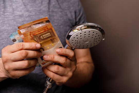 Close up of person holding euro banknotes next to a shower head, symbolizing cost, expens