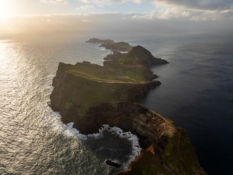 Aerial view of the rugged cliffs and volcanic rock formations of Ponta de Sao Lourenco peninsula under golden sunlight in Canical, Madeira, Portugal.