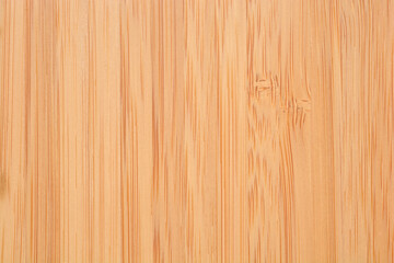 Fototapeta premium A close up view of a natural bamboo wood surface showing fine vertical grain patterns and a warm light brown color texture