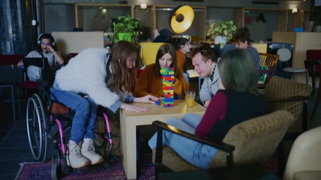 A diverse group of students, including individuals with disabilities, enjoy a lively game of stacking blocks.