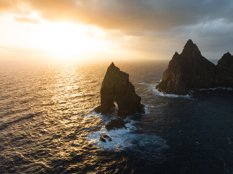 Aerial view of the dramatic rock formations of Ponta de Sao Lourenco during a golden sunset over the dark Atlantic Ocean in Canical, Madeira, Portugal.