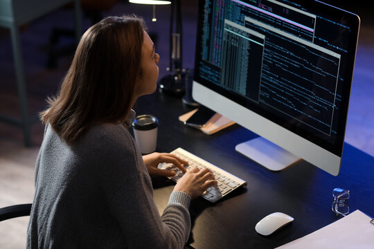 Female programmer working with computer in office at night