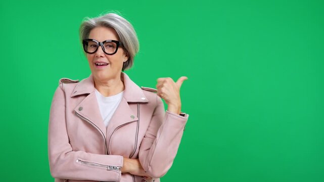 Stylish senior woman pointing aside on green screen