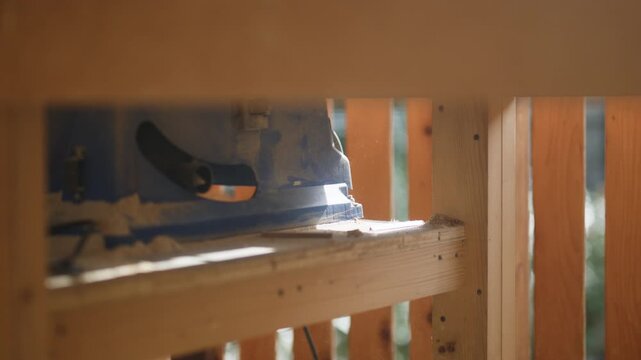 A dedicated carpenter meticulously sands a piece of wood, creating fine dust. The skilled worker focuses on his task, wearing essential safety gear for protection.