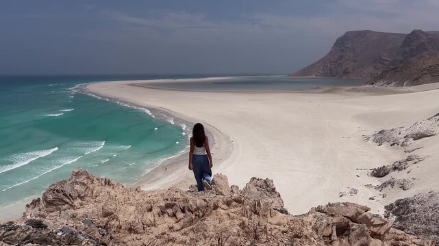 Woman raising arms and celebrating on top of a cliff, socotra island