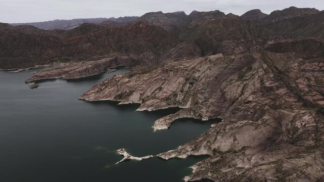 Aerial view of lake Los Reyunos in Mendoza, Argentina, on a dark, overcast day.