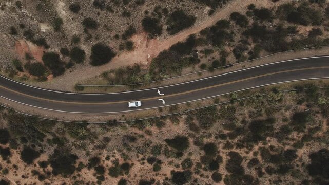 Top down view of a car and driving across the desert on a dark cloudy day.