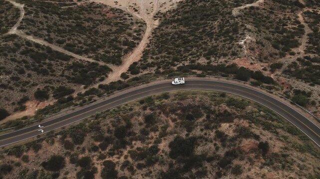 Aerial view. of a camper truck driving on a tarmac road on a dark cloudy day.