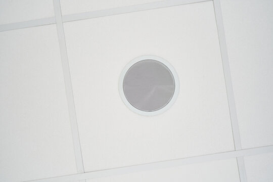 Circular loudspeaker embedded in white suspended ceiling