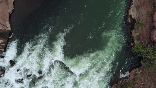 Aerial top down view of a whitewater river stream on a dark cloudy day.