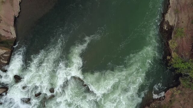 Aerial top down view of a whitewater river stream on a dark cloudy day.