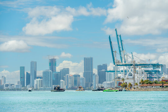Dynamic harbor scene with tugboats and Miami city skyline. Wide angle shot of multiple boats in Miami harbor with a background of skyscrapers and port infrastructure.