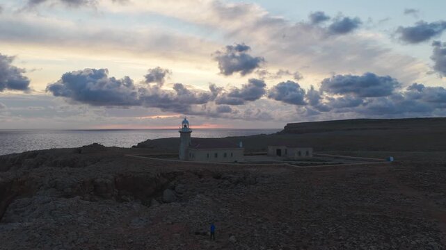 Aerial Dolly Out Lighthouse at Sunset on Rocky Coastline, Punta Nati Menorca Mediterranean