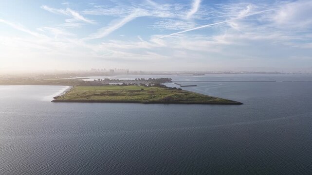 Beautiful morning aerial view revealing Cesar Chavez Park in Berkeley, California, with the sun rising and hazy East Bay cityscape visible in the background