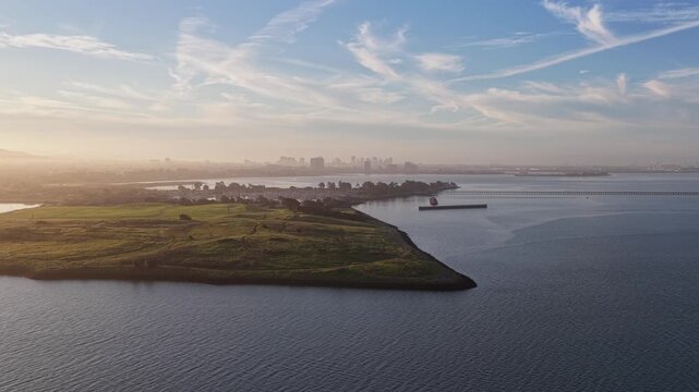 Misty sunrise aerial view of Cesar Chavez Park and Albany Beach in Berkeley, California, with the calm waters of the San Francisco Bay and the city skyline visible in the background