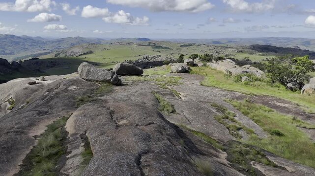 Drone flies over rocky summit chasing the shadow of an overhead cloud on a sunny day at Sibebe Rock near Mbabane, Eswatini